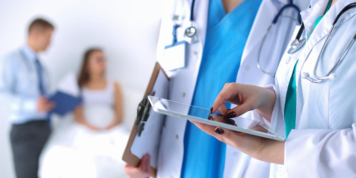 Health care professionals review patient chart on a tablet.